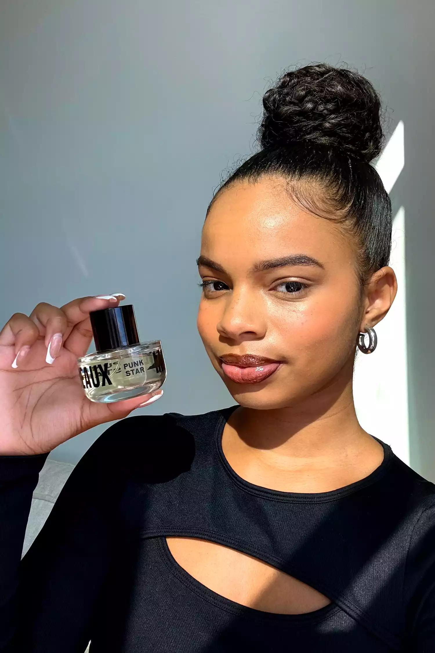 A person holding a bottle of Moodeaux PunkStar INTENSCENUAL Eau de Parfum